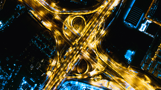 Aerial top view at night scene of Modern Multilevel Motorway Junction with Toll Highway, Road traffic an important infrastructure, Expressway Road and Roundabout, Transportation and travel concept.