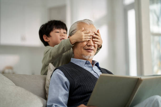 elderly asian grandfather having a good time with grandson at home stock photo