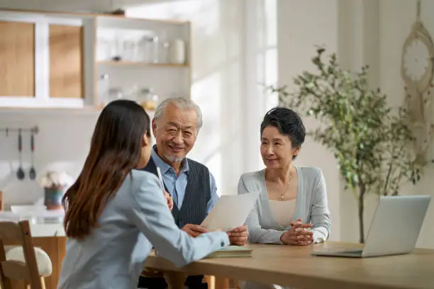 Photo of asian sales woman selling product to old couple