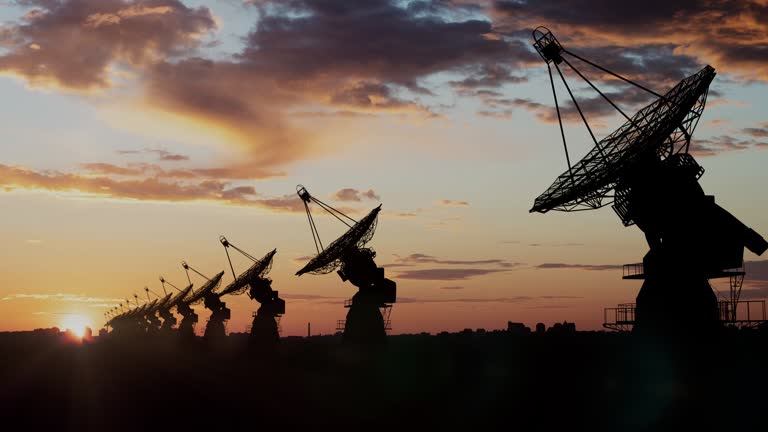 Satellite dishes in a row on a huge field in suburbs at the sunset time