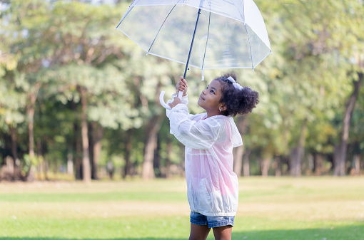 Cute little kid girl playing outdoors in the garden, Child girl with umbrella in the park
