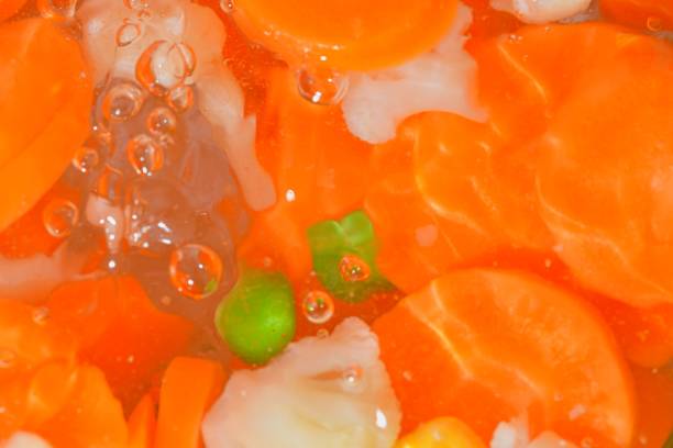 Close-up view of the vegetables with carrots, peas, cauliflower and corn in water background. Texture of boiling soup vetetables drink with macro bubbles. Flat design, top view. Horizontal image. Defocused. vista de cerca de las verduras con zanahorias, guisantes, coliflor y maíz en el fondo del agua. textura de la sopa hirviendo bebida vetetables con macro burbujas. diseño plano, vista superior. imagen horizontal. desenfocado.vista de primer plano de las v