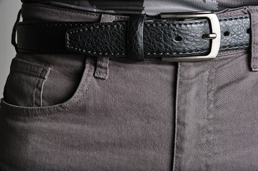 Buttoned black, male leather belt worn on jeans