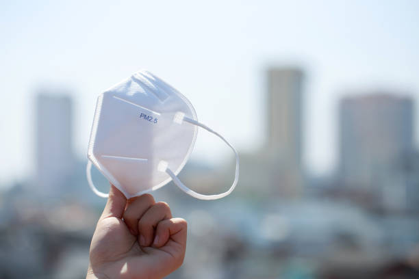 istock Hand-holding pm 2.5 face protection mask for protection against pollution, virus, flu, and coronavirus (Covid-19). Protection pm 2.5. Air face mask. Medical mask. Toxic haze in the city. 1465195111