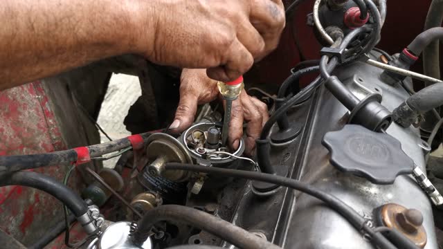 Car engine repair technician screwing contact-breaking points.