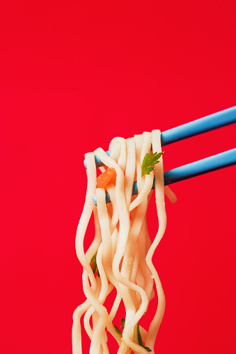 Instant noodles ramen soup on bowl and chopsticks on red background