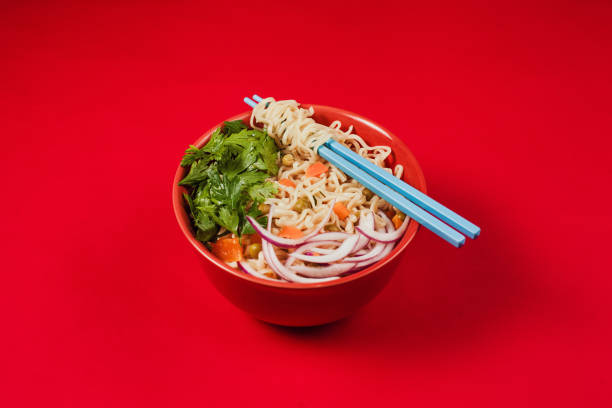 sopa de ramen de fideos instantáneos en un tazón y palillos sobre fondo rojo - noodle soup fotografías e imágenes de stock