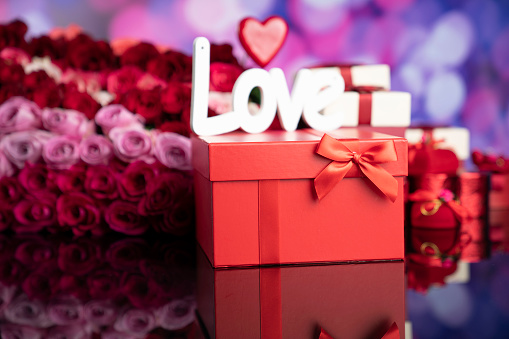 Gifts in boxes and big bouquet of natural roses on blue bokeh background.