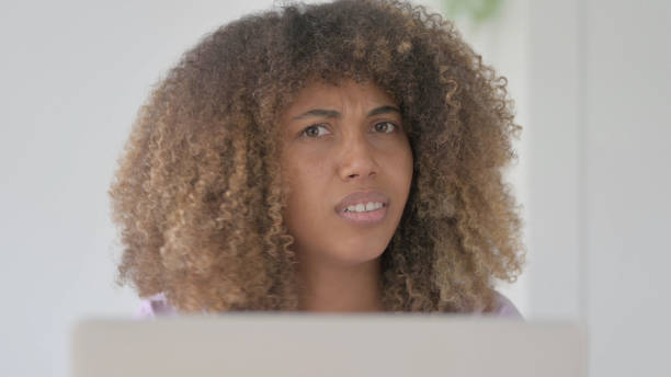 istock Close Up of Young African Woman Shaking Head in Rejection While using Laptop 1465202801