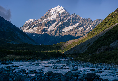 New Zealand snowcapped mountain at sunset with a river and blue sky
