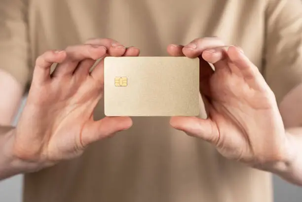 Bank card mock-up, gold sample template in female hands. Blank debit credit plastic bankcard with chip. High quality photo