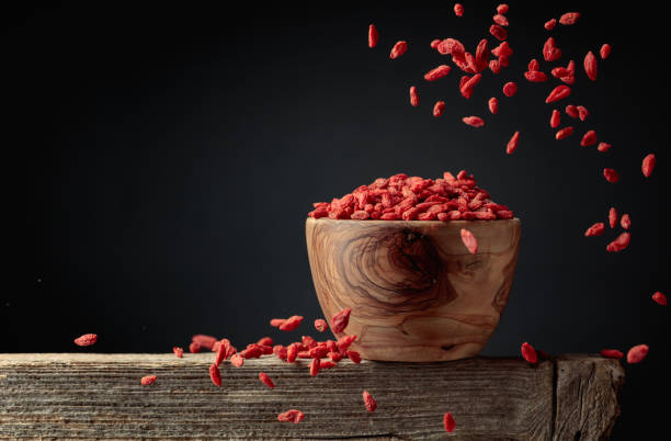 le bacche di goji essiccate vengono versate in una ciotola di legno. - lycium chinese foto e immagini stock