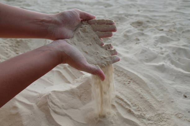 istock sand spills out of female hands on a sandy beach 1465215375