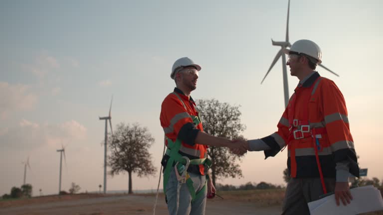 Two engineers standing handshake in a wind turbine station.