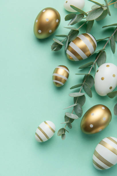 istock Easter eggs painted in gold and eucalyptus branches on a soft green background. 1465216696