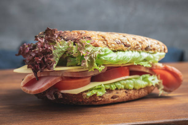 istock Sandwich with a ham, cheese, tomato, salad lettuce on a wooden board 1465218648