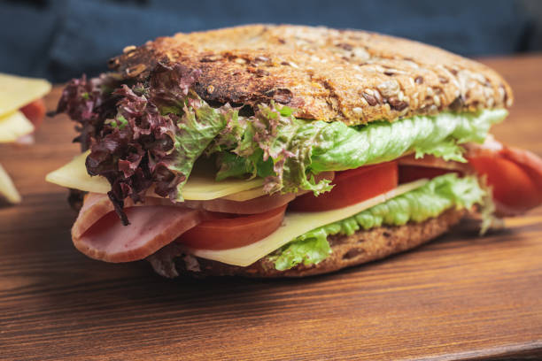 istock Sandwich with a ham, cheese, tomato, salad lettuce on a wooden board 1465218664