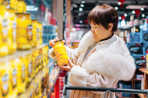 Middle-aged women check the label of canned yellow peach - healthy diet, healthy lifestyle