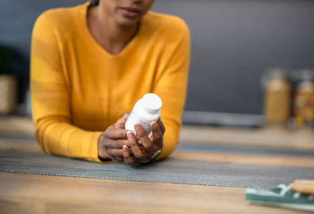 Woman Holding Pill Bottle A woman is holding and reading about the side effects of pills in a bottle. Health and wellbeing concept. prescription medicine stock pictures, royalty-free photos & images