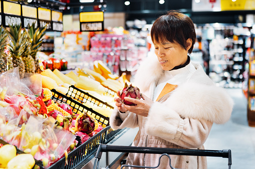 A middle-aged woman selects pitaya in the market - healthy lifestyle, green life，Healthy diet