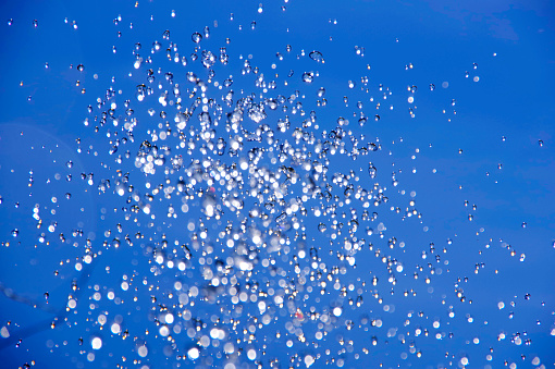 Water drops flying in the air on a blue background.