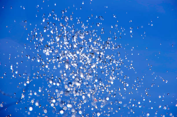a água cai voando no ar sobre um fundo azul. - rain snow sun beauty - fotografias e filmes do acervo