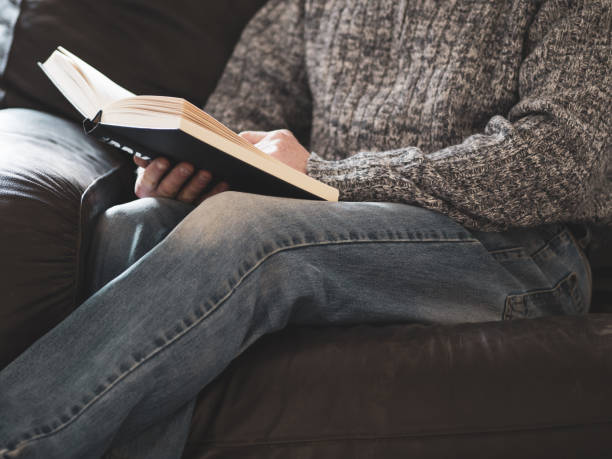 istock man reading a book sat on chair 1465226324