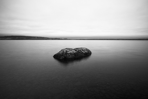 An aerial grayscale view of a rock formation in Lake Mjosa, Norway