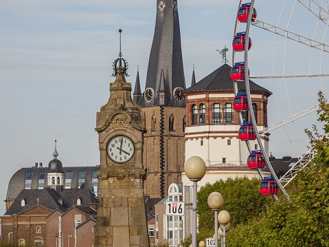 Dusseldorf, Germany – October 25, 2022: A clock tower and church behind Ferris wheel at the city of Dusseldorf in Germany