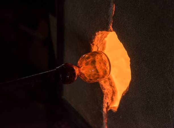 istock Glass blower holding orange glass mold with high temperature fire for shaping 1465228644