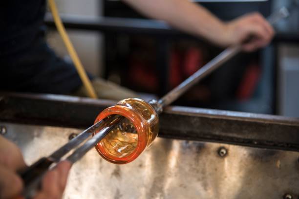 istock Glass blower holding orange glass mold with high fire for shaping 1465228654