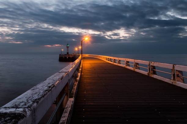 istock Lighthouse on the wooden bridge against a clouded sky 1465234280