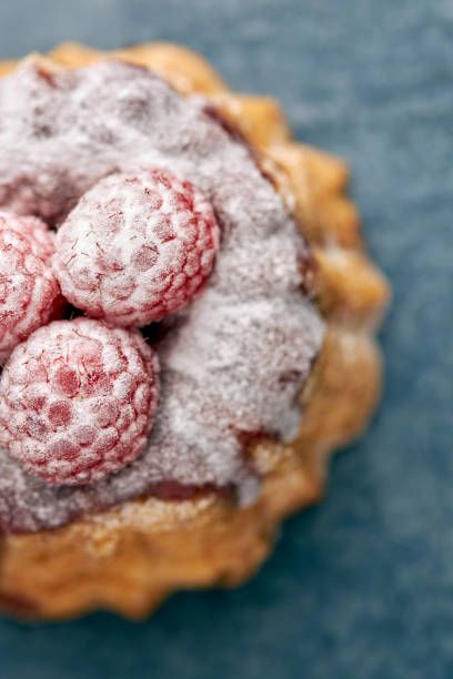 Top view of a delicious raspberry tea cake on blue background