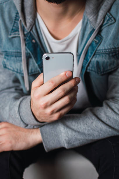 istock Vertical shot of a sitting guy scrolling through his smartphone 1465234530