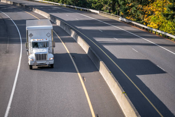istock Local compact middle power rig semi truck transporting cargo in box trailer driving on the turning highway road at sunny day 1465234957