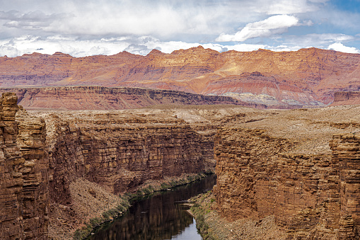 The image is a beautiful view of the Colorado River flowing through Marble Canyon in Arizona and the Vermilion Cliffs beyond the canyon