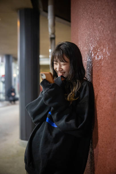 istock Young woman leaning on wall and reading message on smart phone 1465235042