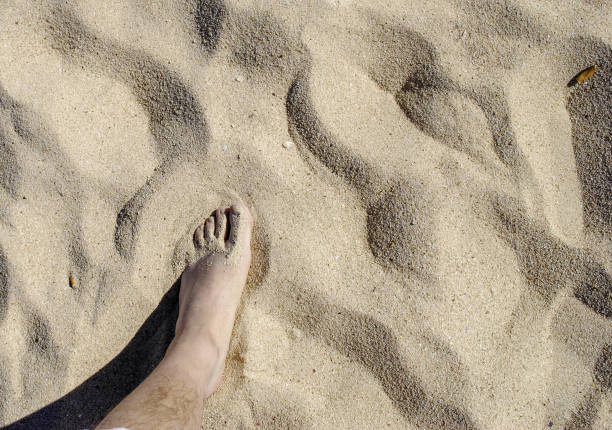 istock Man's foot on the sand on the beach 1465235106