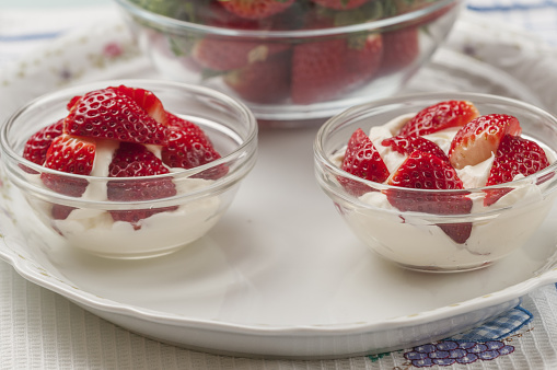 A closeup of fresh strawberries with cream in a glass bowl