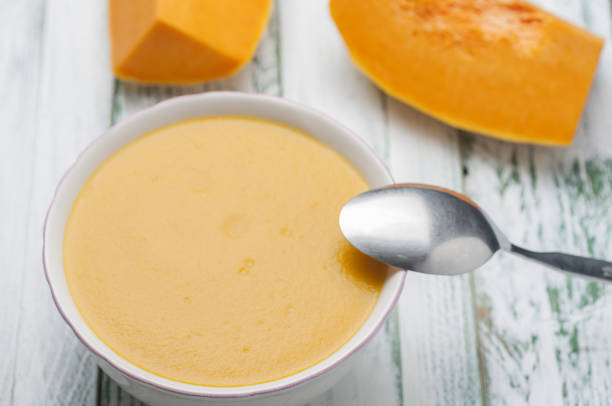 A healthy pumpkin cream soup in a bowl with a spoon
