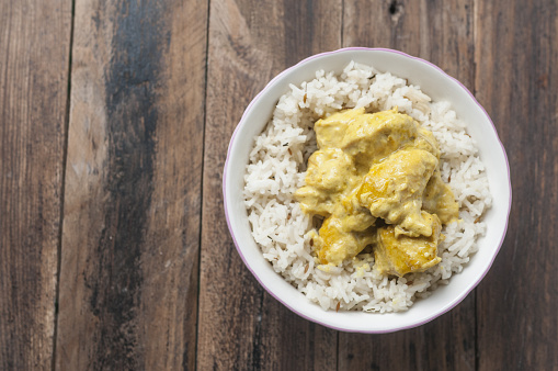 A top view of a chicken with curry sauce served with rice basmati in a small bowl with a copy space