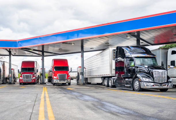 Long haulers big rigs semi trucks with semi trailers fuel tanks with diesel standing on the gas station on the truck stop stock photo