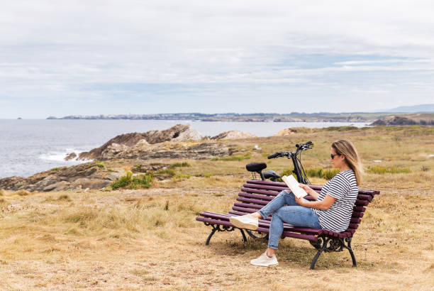 istock Woman sitting on a bench reading a book outdoor 1465237624