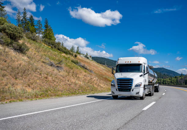 istock Long haul low cab profile white big rig semi truck transporting liquid cargo in tank semi trailer driving on the winding mountain road 1465238648