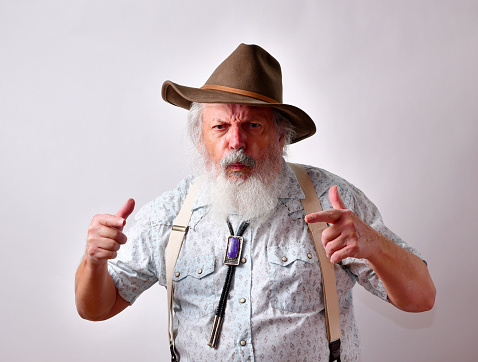 An angry and frustrated senior Caucasian male in a hat on white background