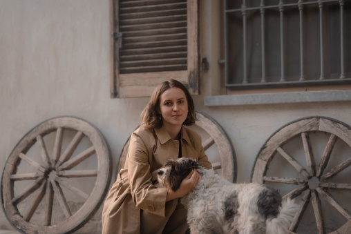 A girl in a brown coat with a dog.