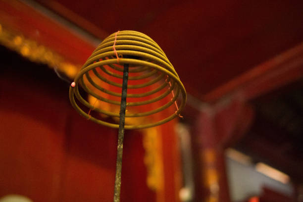 Close up picture of many burning incense sticks with some people standing behind at Wat Phnom in Phnom Penh, Cambodia