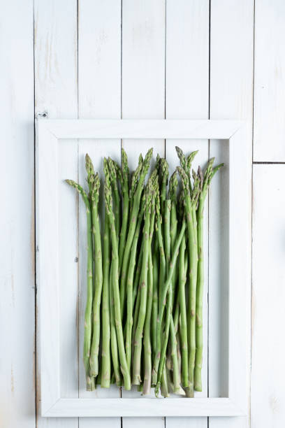 istock Asparagus in a frame on a white old wooden board 1465245824