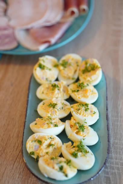 istock Closeup shot of appetizing cut eggs with ham pieces on a blue pla 1465246092