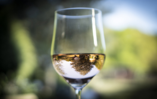 A shallow depth of field shot of a glass with water reflecting another scenery.